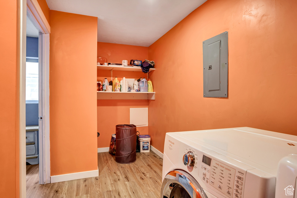 Clothes washing area featuring light hardwood / wood-style flooring, washing machine and clothes dryer, and electric panel