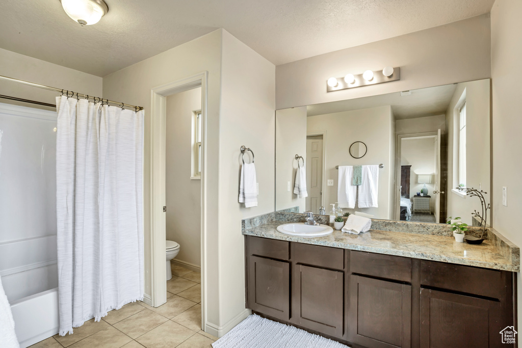 Full bathroom with shower / bath combo with shower curtain, vanity, tile patterned flooring, and toilet