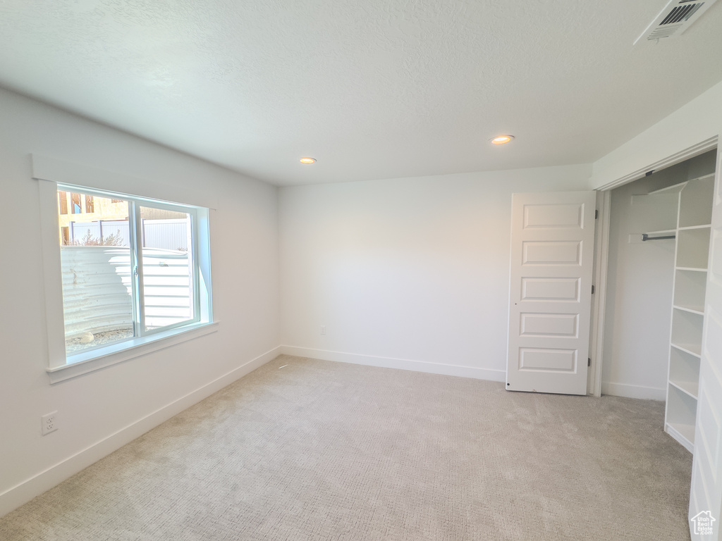 Unfurnished bedroom with a textured ceiling, a closet, and light colored carpet