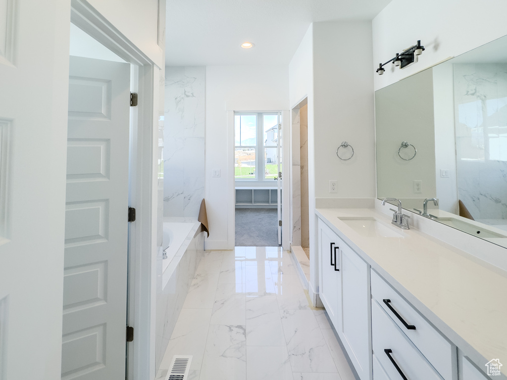 Bathroom featuring a relaxing tiled tub and vanity