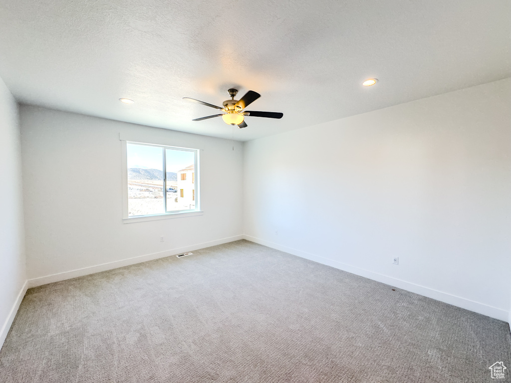 Carpeted empty room featuring a textured ceiling and ceiling fan