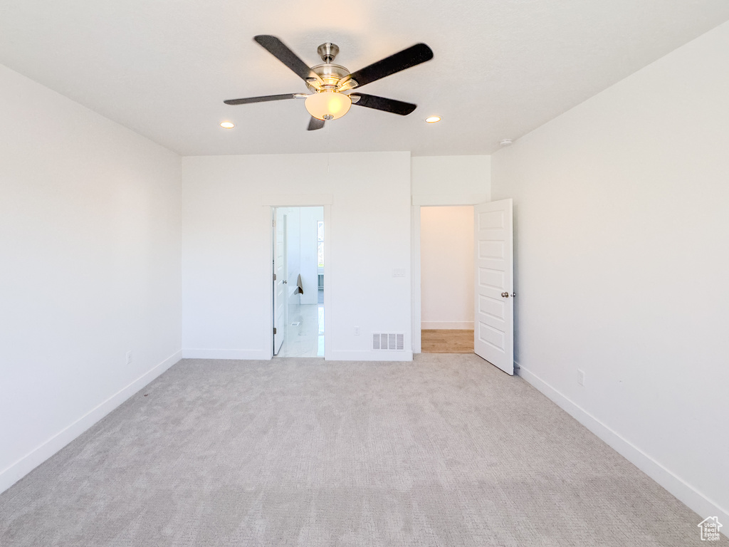 Unfurnished bedroom featuring light carpet, ensuite bath, and ceiling fan