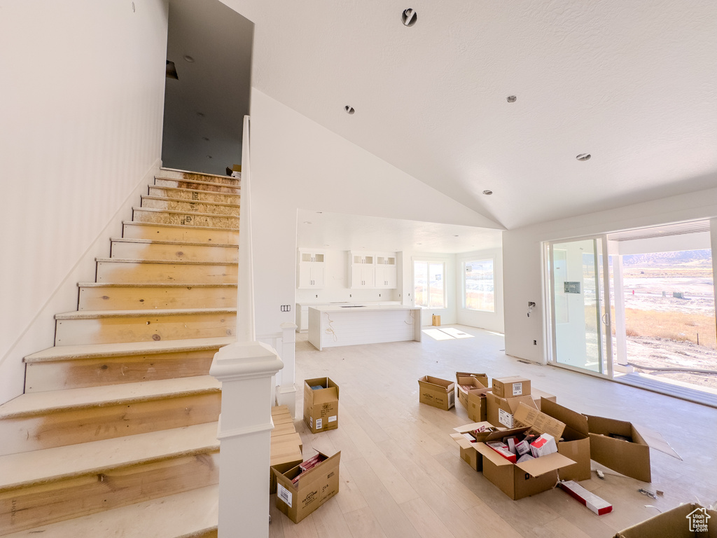 Staircase with high vaulted ceiling and hardwood / wood-style floors