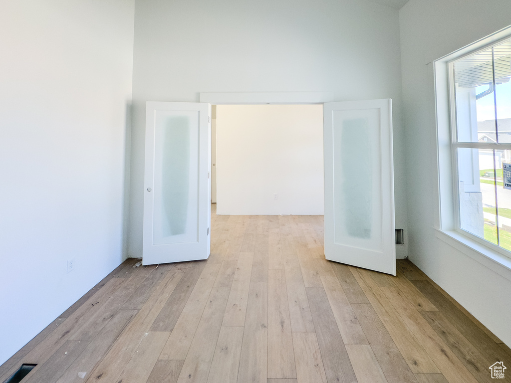 Spare room featuring plenty of natural light, a high ceiling, and light hardwood / wood-style flooring