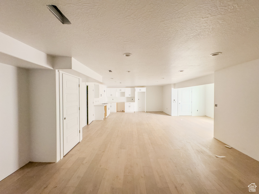 Unfurnished living room with a textured ceiling and light hardwood / wood-style floors