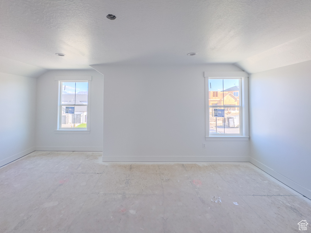 Additional living space with vaulted ceiling, a wealth of natural light, and a textured ceiling