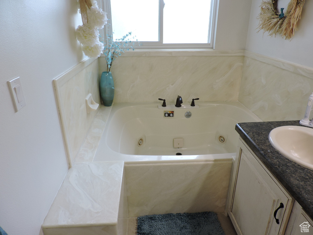 Bathroom featuring tile patterned flooring, vanity, and a washtub