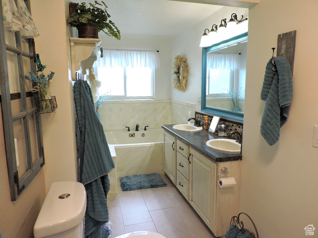 Bathroom with double sink vanity, a washtub, and tile patterned flooring