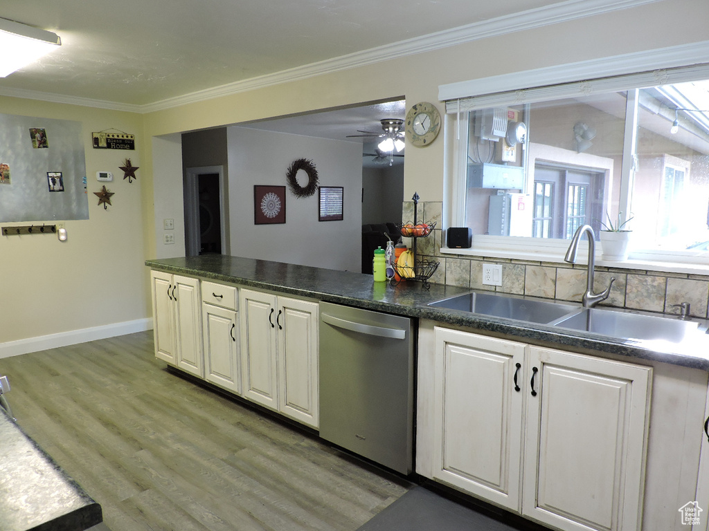 Kitchen with white cabinets, ceiling fan, sink, stainless steel dishwasher, and light hardwood / wood-style floors