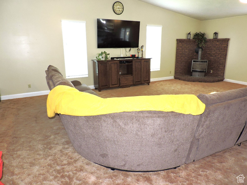 Living room with a wood stove, carpet flooring, and vaulted ceiling