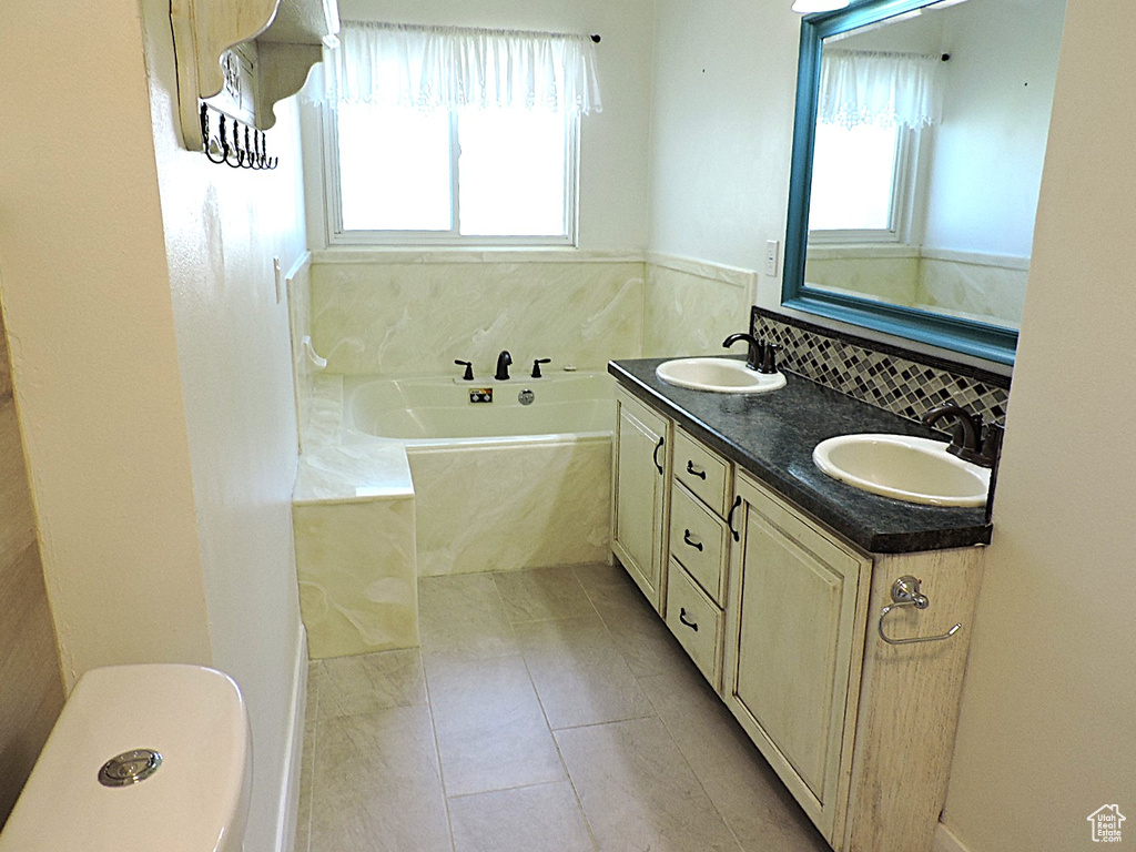 Full bath featuring a sink, tile patterned flooring, double vanity, and a bath