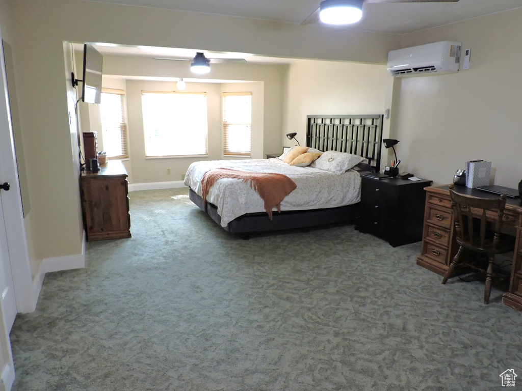 Bedroom with ceiling fan, a wall mounted air conditioner, and carpet floors