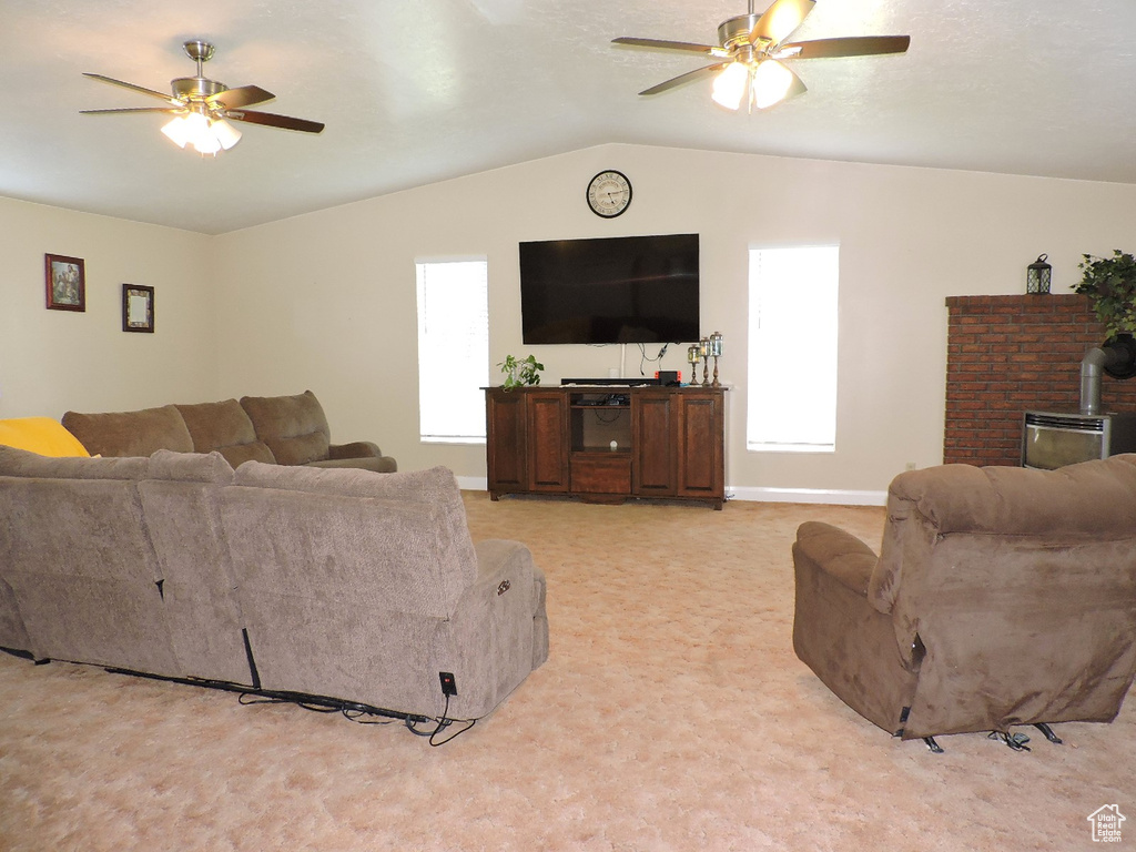 Living room with ceiling fan, a wood stove, and a wealth of natural light