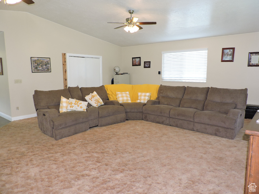 Carpeted living room with ceiling fan and vaulted ceiling