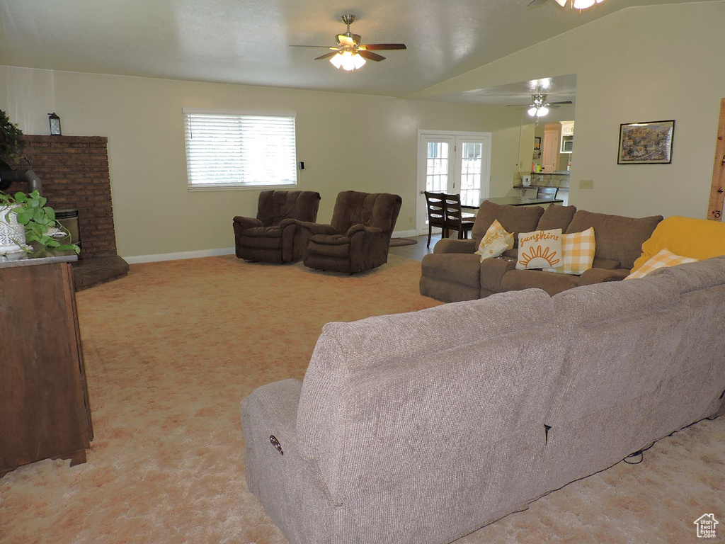 Living room featuring ceiling fan, vaulted ceiling, a healthy amount of sunlight, and light carpet