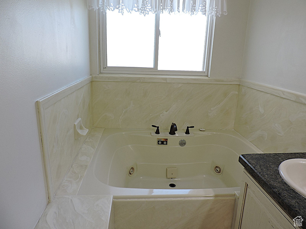 Full bathroom with plenty of natural light, a tub with jets, and vanity