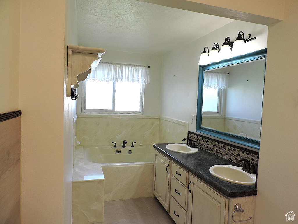 Full bath featuring a sink, tile patterned floors, a garden tub, and double vanity