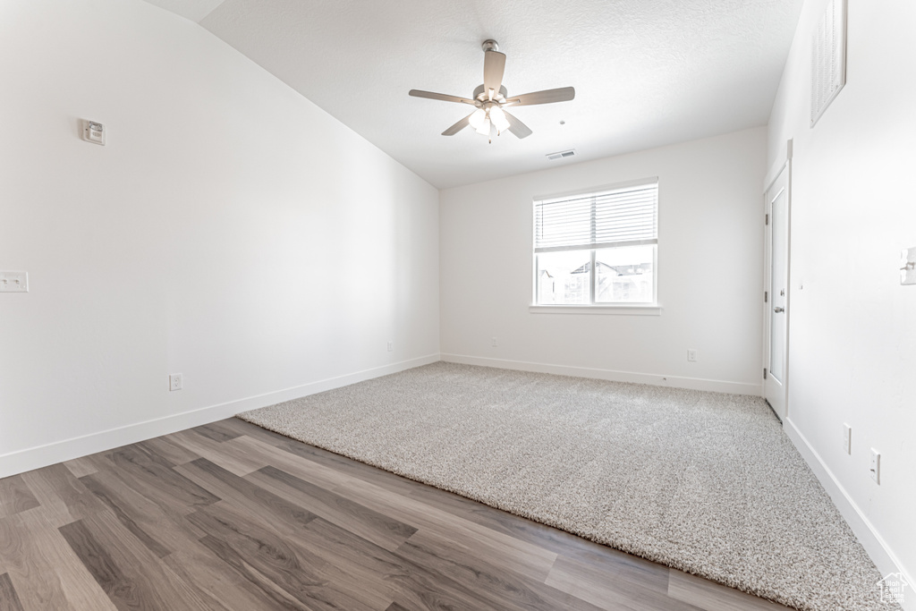 Spare room with ceiling fan, vaulted ceiling, and wood-type flooring