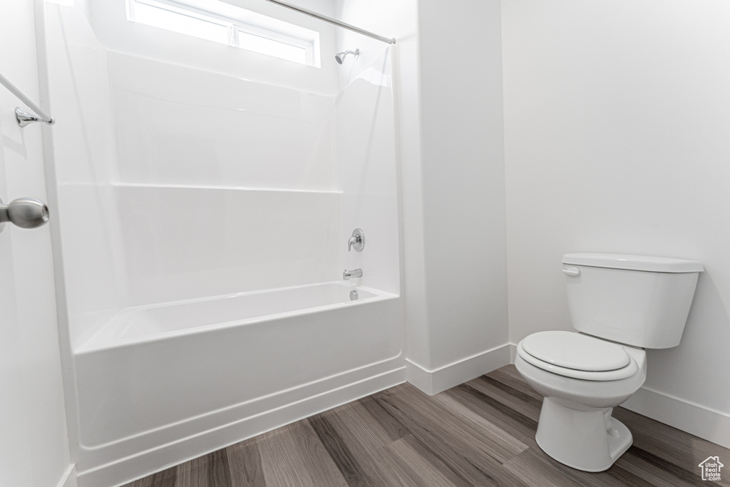 Bathroom featuring hardwood / wood-style floors, shower / washtub combination, and toilet