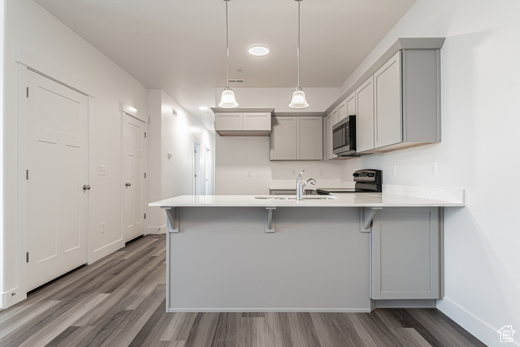 Kitchen featuring gray cabinetry, stainless steel appliances, pendant lighting, sink, and kitchen peninsula