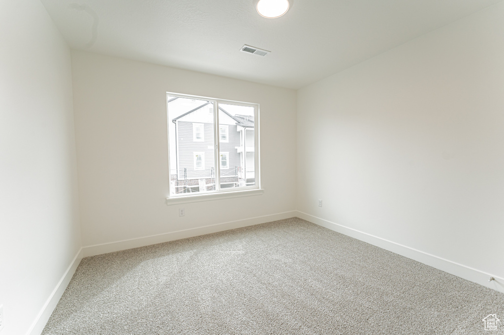 Unfurnished room featuring light carpet, baseboards, and visible vents