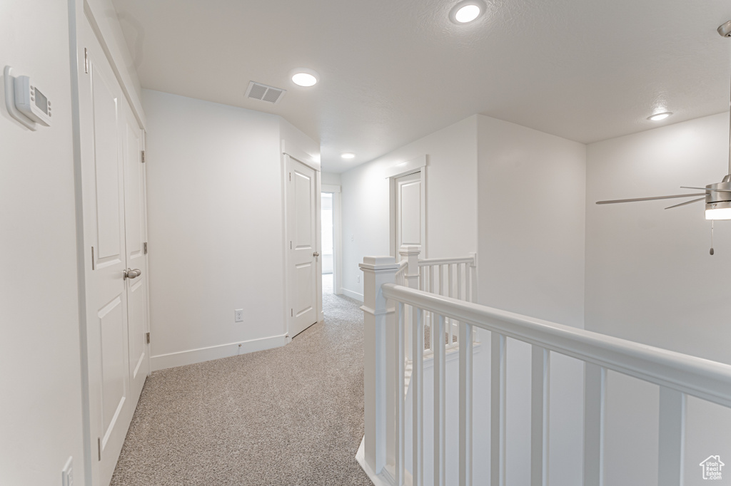 Hall with an upstairs landing, light carpet, baseboards, visible vents, and recessed lighting