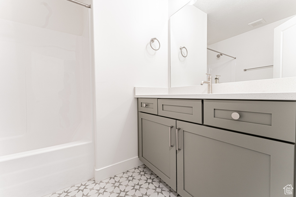 Full bathroom with tile patterned floors, vanity, shower / washtub combination, baseboards, and visible vents