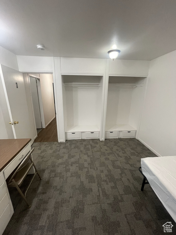 Unfurnished bedroom with dark carpet and two closets