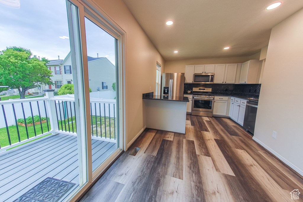 Kitchen with dark wood-type flooring, stainless steel appliances, backsplash, and white cabinets