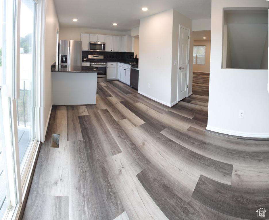 Kitchen with white cabinetry, decorative backsplash, dark hardwood / wood-style floors, and stainless steel appliances