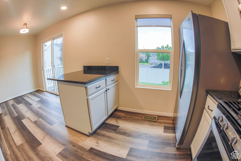 Kitchen featuring dark stone counters, white cabinets, kitchen peninsula, and light wood-type flooring