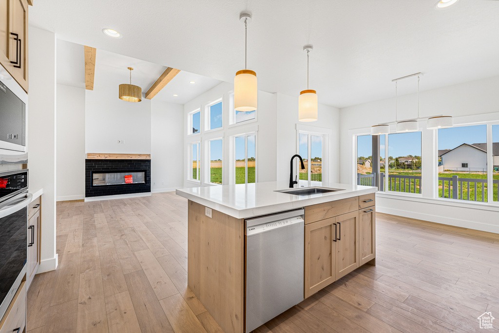 Kitchen featuring light brown cabinetry, decorative light fixtures, appliances with stainless steel finishes, and plenty of natural light