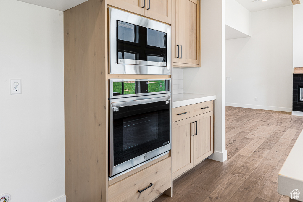 Kitchen with light hardwood / wood-style flooring, appliances with stainless steel finishes, and light brown cabinets