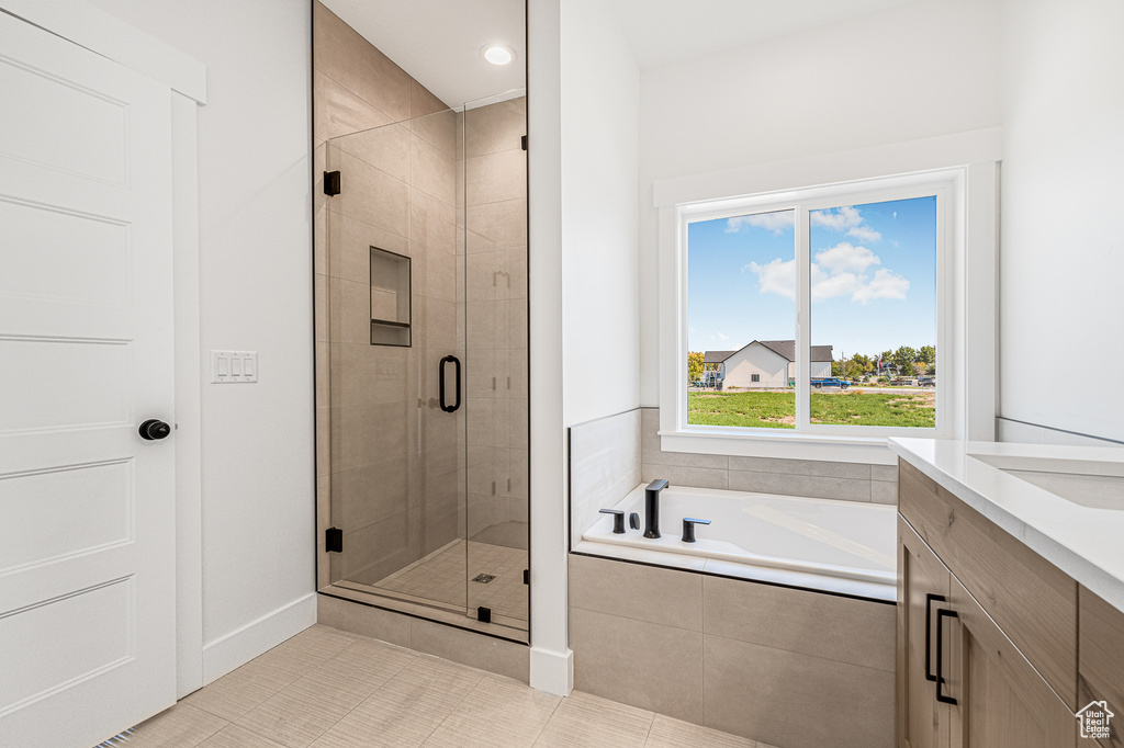 Bathroom featuring shower with separate bathtub, tile patterned flooring, and vanity