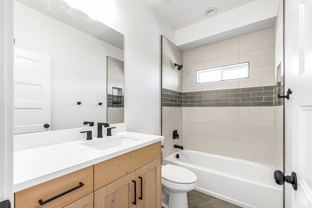 Full bathroom with tile patterned flooring, tiled shower / bath combo, vanity, and toilet