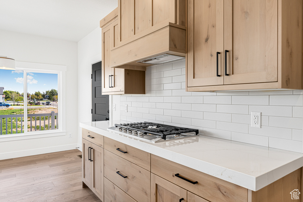 Kitchen featuring stainless steel gas stovetop, backsplash, light wood-type flooring, and light brown cabinetry