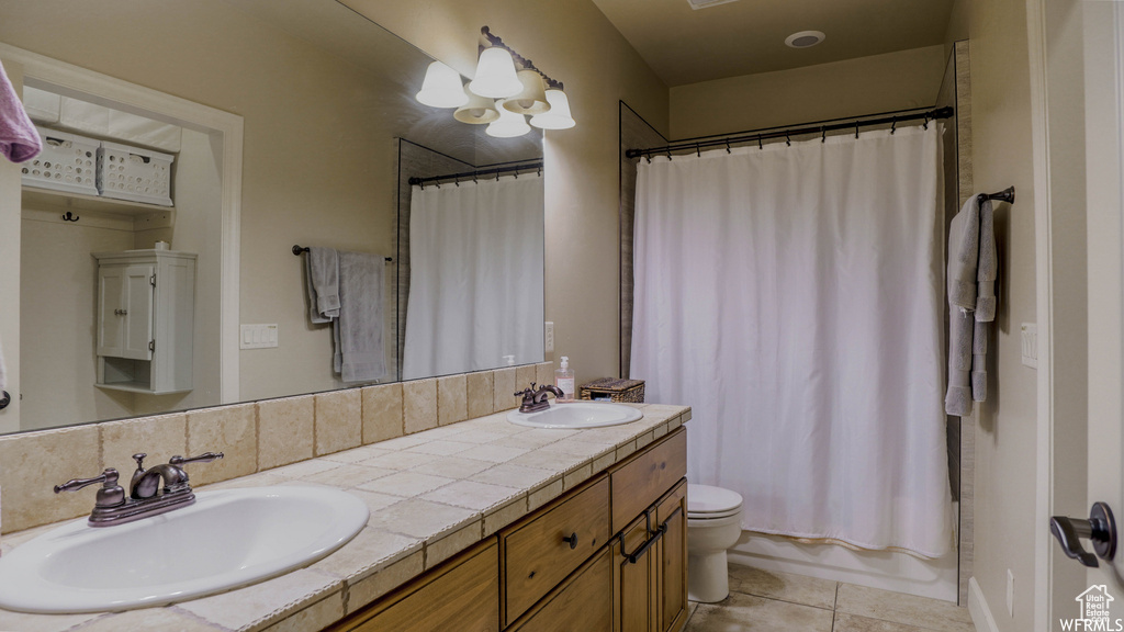 Bathroom featuring double vanity, toilet, and tile patterned floors