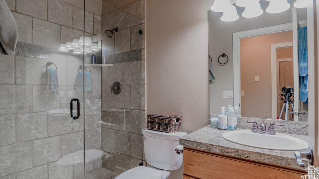 Bathroom featuring walk in shower, vanity, and toilet