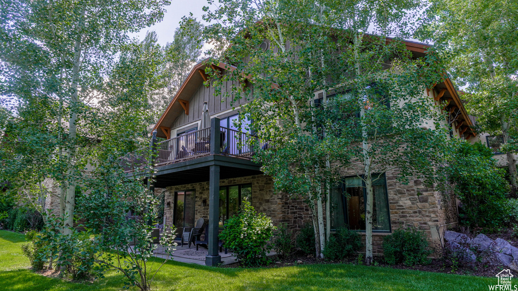 Back of property featuring a lawn and a balcony