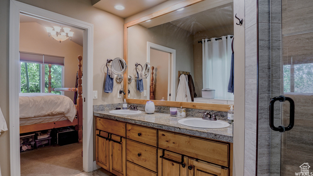 Bathroom with double sink vanity, walk in shower, vaulted ceiling, and an inviting chandelier