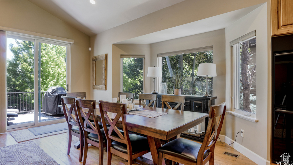 Dining room with lofted ceiling, plenty of natural light, and light hardwood / wood-style floors