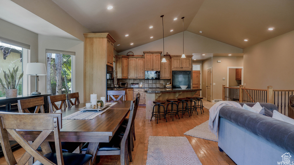 Dining room featuring high vaulted ceiling and light hardwood / wood-style flooring