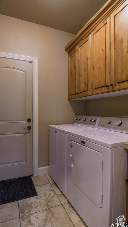 Washroom with cabinets, light tile patterned floors, and washer and clothes dryer