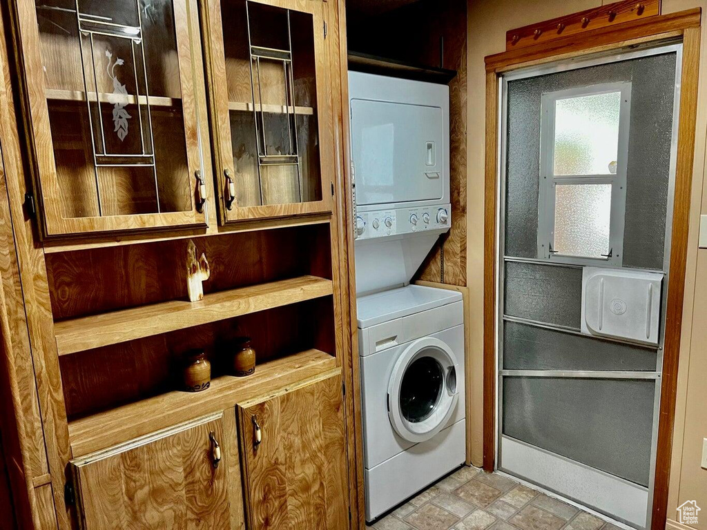 Laundry area featuring stacked washer / dryer and light tile patterned floors
