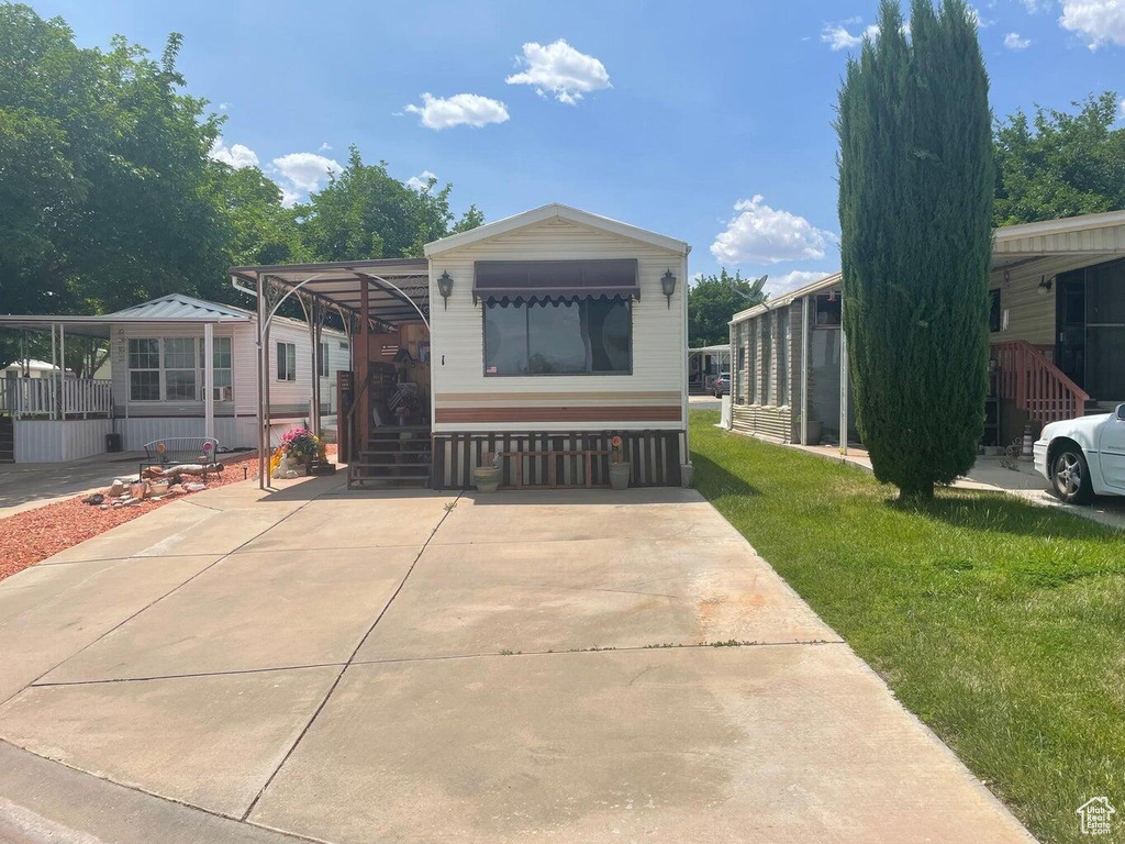 View of front of property with a carport and a front yard