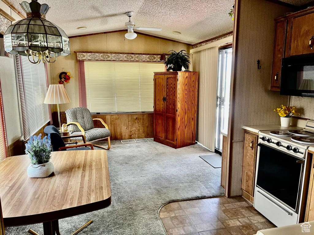 Kitchen featuring ceiling fan, white range, vaulted ceiling, and a healthy amount of sunlight