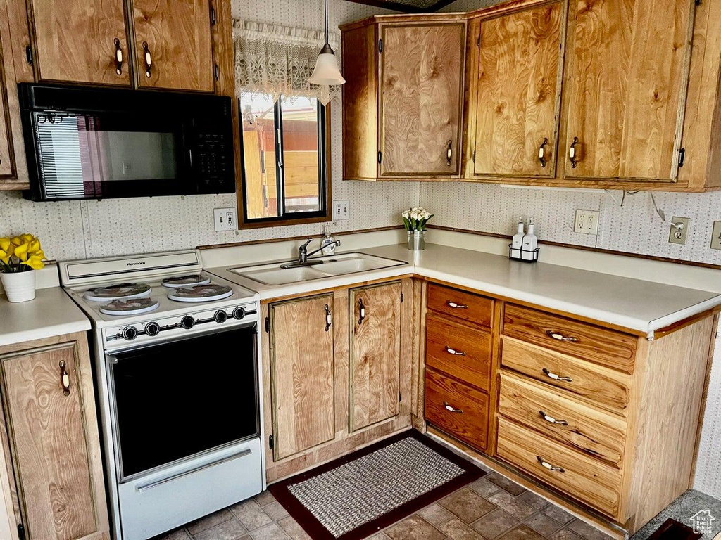 Kitchen featuring white range oven, pendant lighting, and sink