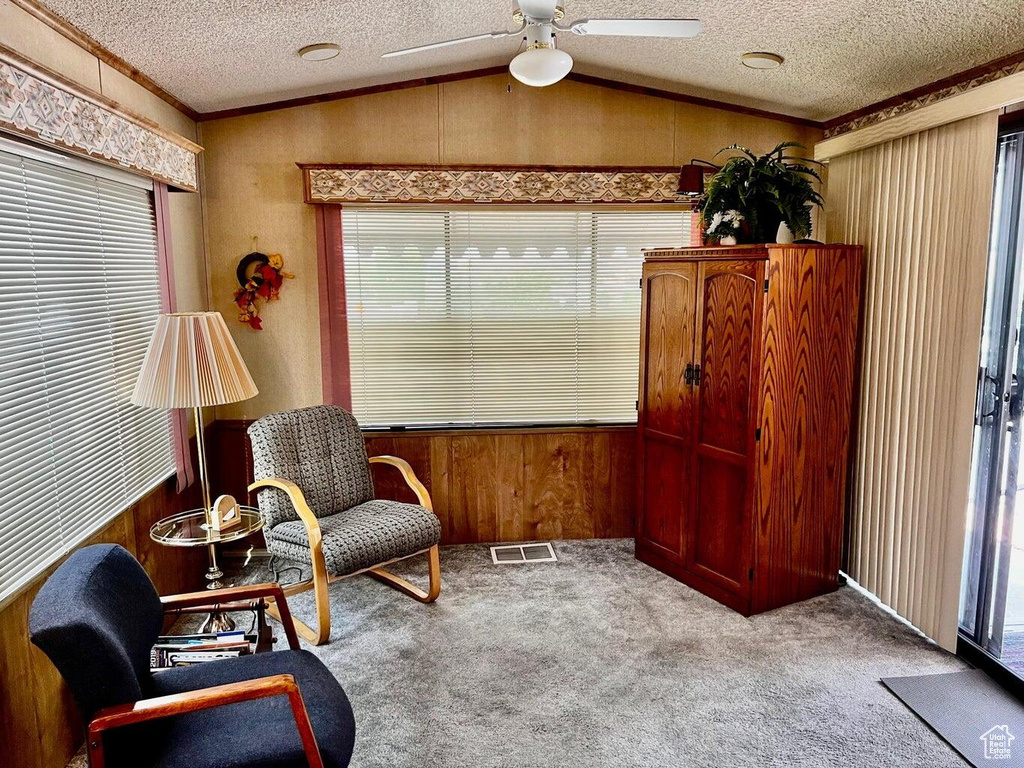 Sitting room with lofted ceiling, carpet floors, plenty of natural light, and ceiling fan