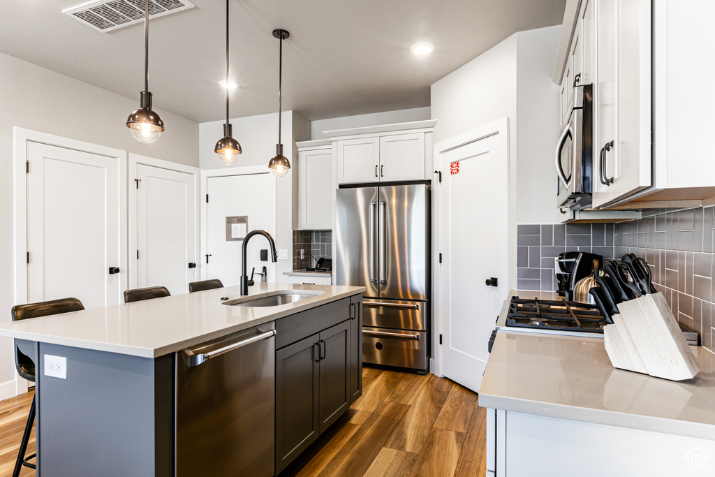 Kitchen with an island with sink, sink, tasteful backsplash, and stainless steel appliances