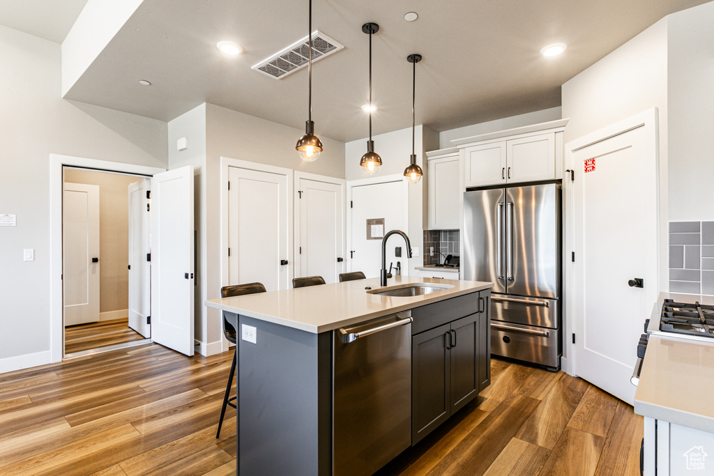 Kitchen with a center island with sink, sink, stainless steel appliances, and backsplash